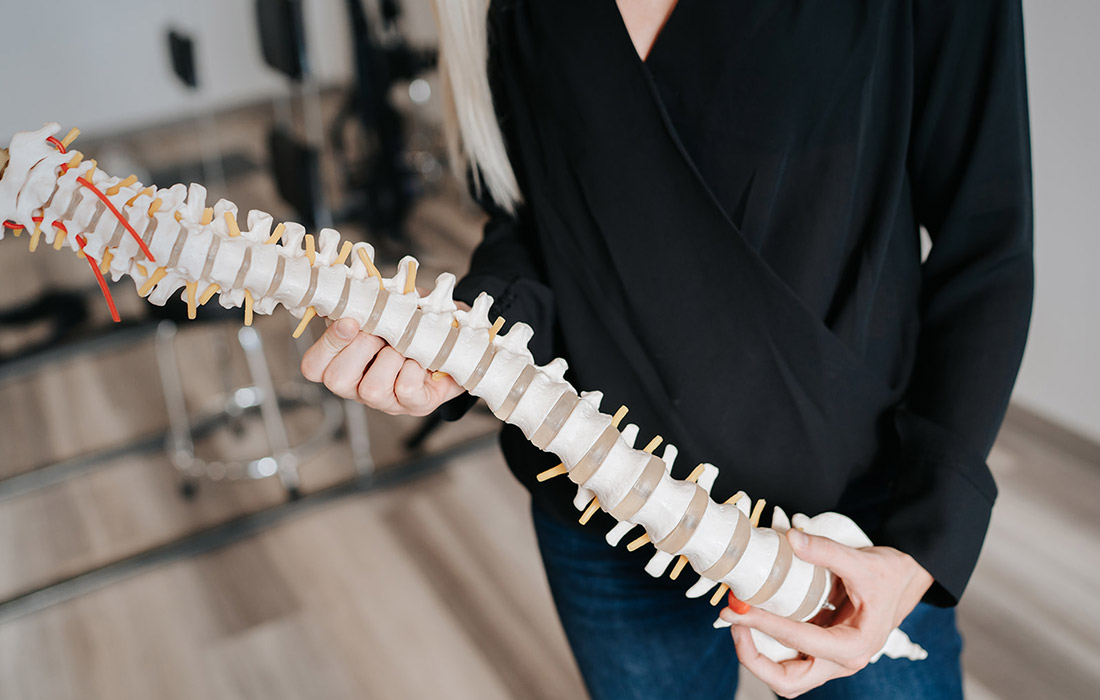 Dr. Emily Payne, Chiropractor displaying a model of a spine to explain scoliosis and scoliosis care in Fargo, ND