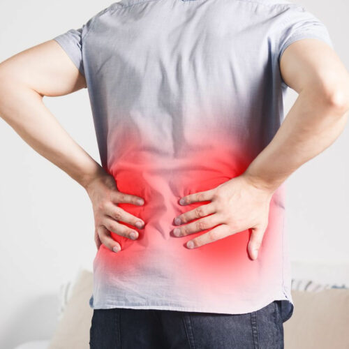 man standing holding his back in pain from his sciatica